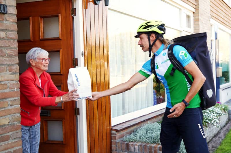 Een fietskoerier overhandigd medicijnen aan apotheek klant